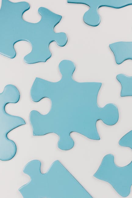 pexels-photo-8385737-8385737 Close-up of blue puzzle pieces scattered on a white surface, conceptual and minimalistic.