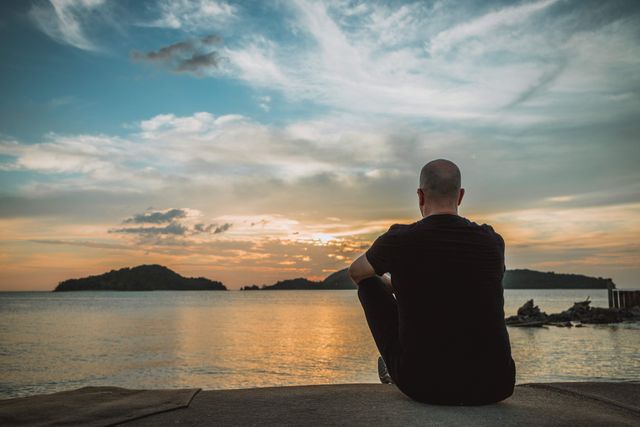 pexels-photo-31335115-31335115 A man sits by the beach watching a vibrant sunset in Langkawi, Malaysia, captured in stunning detail.